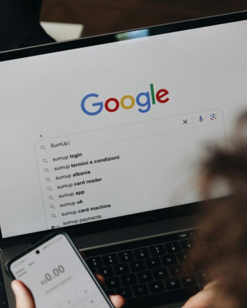 A person holding a cell phone and a laptop