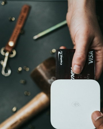 person holding Visa card and white device