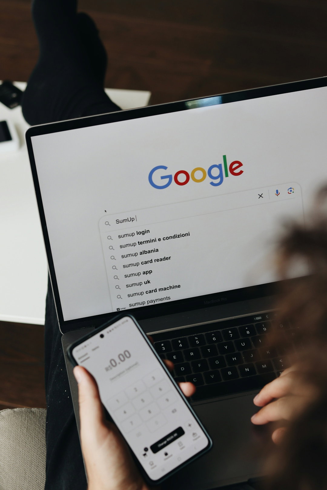 A person holding a cell phone and a laptop